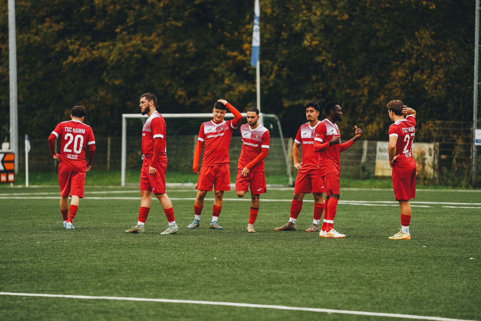 Joueurs amateurs sur un terrain de football urbain à Antony, avec immeubles et espaces verts en arrière-plan.